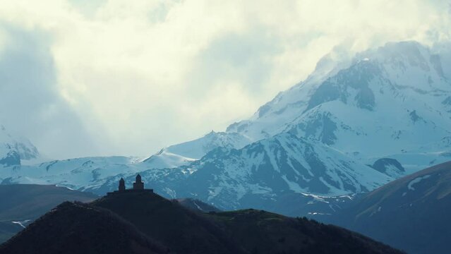 great Caucasus mountains and ancient Gergeti Trinity Church in Kazbegi, Georgia. High quality 4k footage