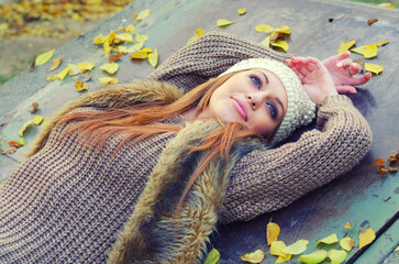 Beautiful smiling young woman lying in the autumn forest