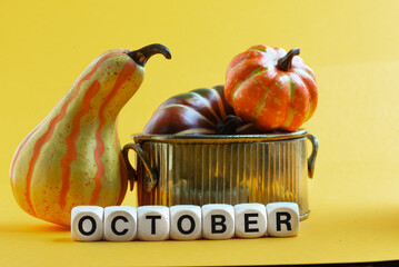 Autumn concept. On a yellow background are multi-colored pumpkins in a bowl and the inscription...
