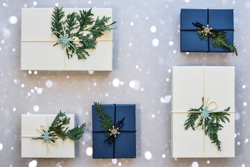 Ivory and blue Christmas gifts in a pattern on gray background with white snow bokeh