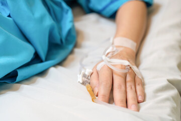 Obraz na płótnie Canvas Asia patient woman lying on the bed with saline solution and syringe line on her hand in hospital ward. Emergency and treatment. Healthcare and medical concept