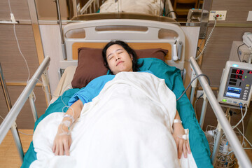 Patient Asia woman on the bed with saline solution and monitor blood pressure at hospital ward room. Treatment emergency recovery after surgery. Hypertension and hypotension. Healthcare and medical