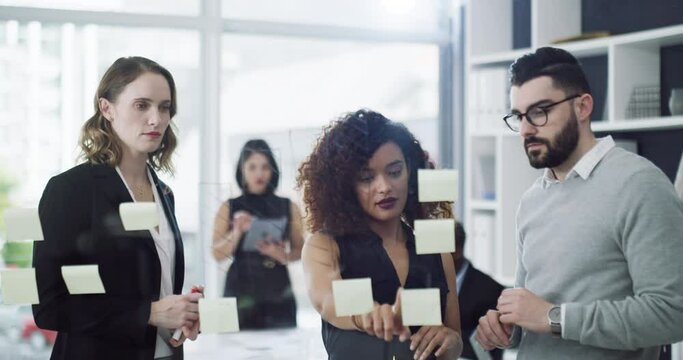 Teamwork, unity and innovation at work. Group of business people working together to meet a deadline. Serious creative team planning and sharing ideas, writing on sticky notes and brainstorming