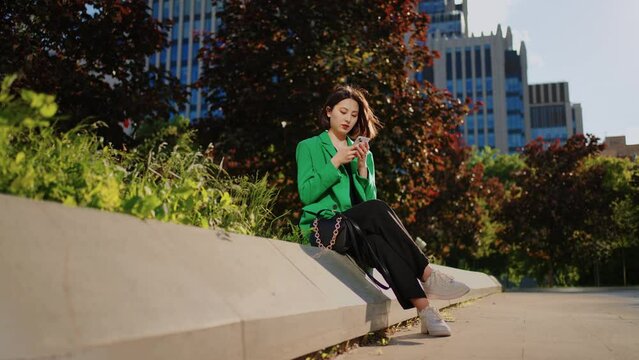 japanese fashionista woman with new smartphone is sittingin park in downtown, viewing social media