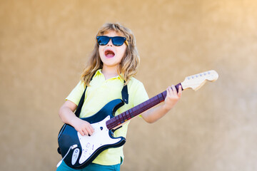 Funny rock child with guitar. Little boy in sunglasses. Kids music concept. Rock and roll guitar....