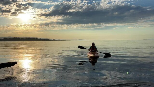 adult woman on a sports holiday she paddles while sitting on a kayak is kayaking for the first time leisure for adults travel agency beautiful weather pacific ocean Parksville beach Surfside RV resort