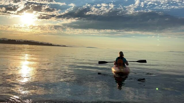 adult woman on a sports holiday she paddles while sitting on a kayak is kayaking for the first time leisure for adults travel agency beautiful weather pacific ocean Parksville beach Surfside RV resort
