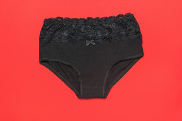 Black women's high-waisted panties on a bright red background. Minimal concept of women's underwear.