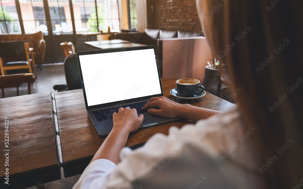 Wall mural mockup image of a woman using and typing on laptop computer with blank white desktop screen in cafe