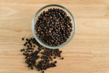 Black pepper in a glass bowl on the wooden table. food, spice, seasoning Concept.