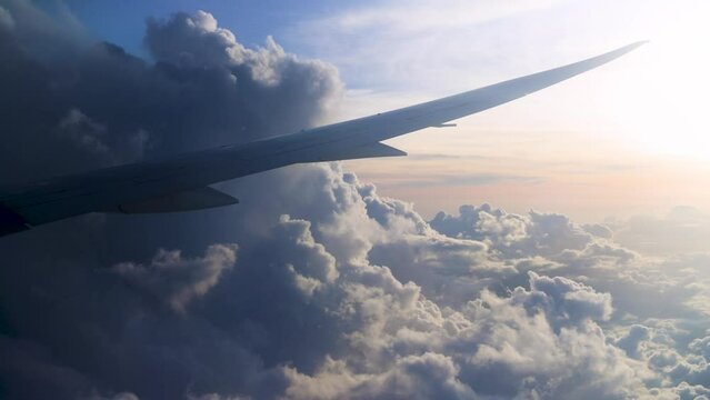 view from the cabin window on the plane wing flying among the clouds on sunset