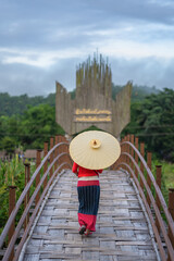 Asian woman dressed in traditional Northern Thailand culture on the longest bamboo bridge (Su Tong Pae bridge) at Suan Tham Phu Sama temple in Mae Hong Son, Thailand.