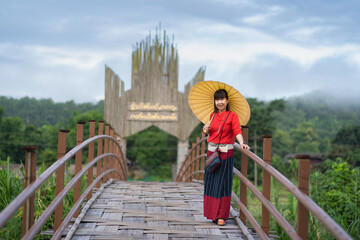 Fototapeta na wymiar Asian woman dressed in traditional Northern Thailand culture on the longest bamboo bridge (Su Tong Pae bridge) at Suan Tham Phu Sama temple in Mae Hong Son, Thailand.