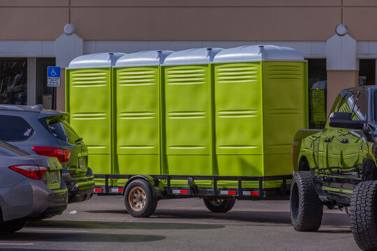 Four Yellow Portable Bathrooms on the Back of a Trailer Being Towed to a Location