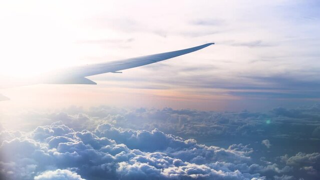 view from the cabin window on the plane wing flying among the clouds on sunset