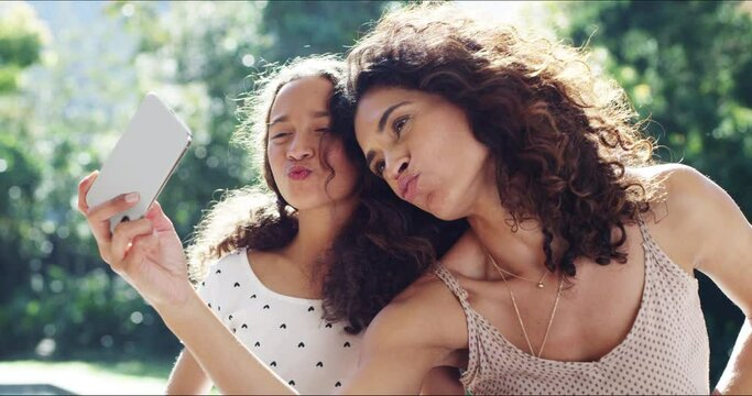 Carefree family taking selfie on phone, making funny faces and bonding in nature together. Mother and daughter taking photos for social media, pouting and relaxing in a park, garden or backyard