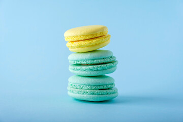 Colorful french macarons cookies (macaroons) on blue background. Dessert, vegetarian sweets close up, stacked balance