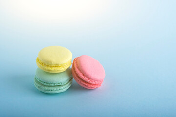 Colorful french macarons cookies (macaroons) on blue background. Dessert, vegetarian sweets close up