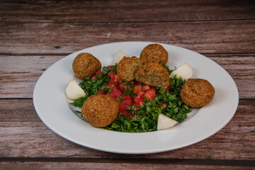 Vegetarian dish, falafel balls from spiced chickpeas with chopped parsley, fresh onions and tomato, tahini sauce, High quality photo