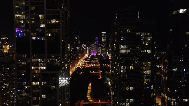Drone Flies between Chicago Skyscrapers at Night. Beautiful Aerial Establishing Shot