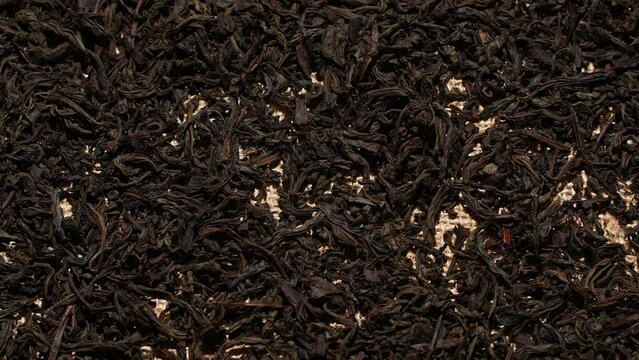 Close-up herbal black or green tea leaves texture on jute sack, food background