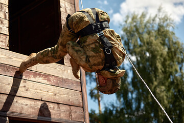Naklejka premium Special forces operator during assault rappeling with weapons. Soldiers rappelling