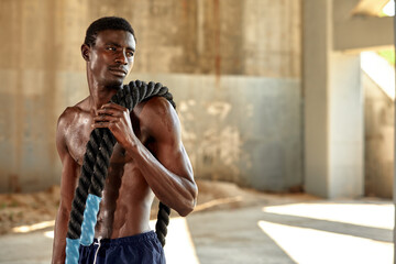 Rope workout. Sport man doing battle ropes exercise outdoor. Black male athlete exercising, doing...