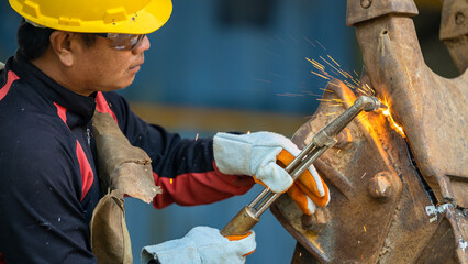 Industrial worker metal cutting with acetylene torch at factory welding steel structure, Welder is...
