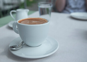 poranna kawa po włosku. Kawa w białej filiżance na spodku na stole z białym obrusem.