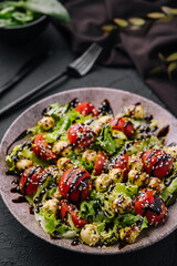 Green salad made with tomatoes, cheese mozzarella balls and sesame on plate