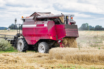 Combine in the field harvests wheat against the blue sky. Close-up.