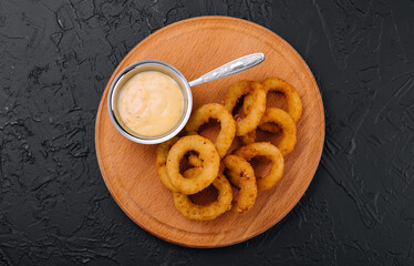 crunchy fried onion rings and sauce on wooden dish