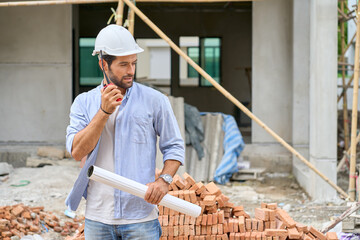 Single Foreman use walkie talkie to hear team speaking in village construction site