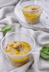 homemade hummus in a plastic cups with basil