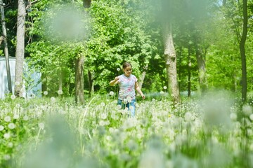A school-age girl in a meadow with dandelions. Recreation in the park.