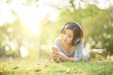 Young girl listening to music with headphone in city park