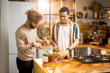 Two guys of different ethnicity cooking healthy vegan food on kitchen at home. Concept of close...