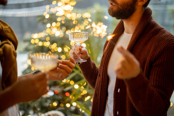 Two male friends celebrating winter holidays, standing together with wine at backyard. Christmas tree on background. Caucasian and hispanic man together. Idea of gay couples and holiday mood