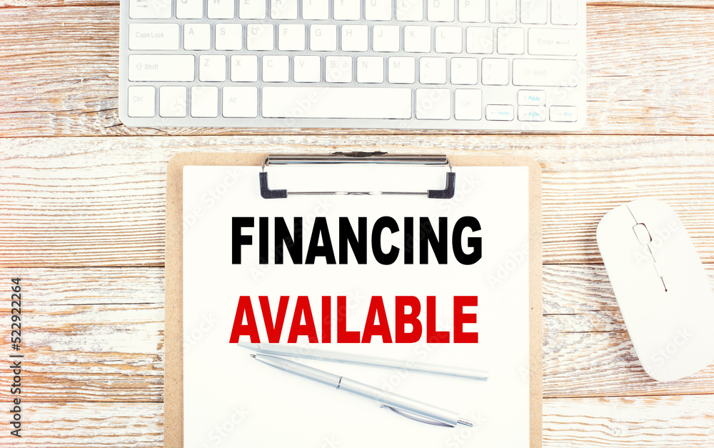 Poster financing available text on a clipboard with keyboard on wooden background