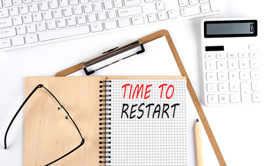 Notebook with the word TIME TO RESTART with keyboard and calculator on the white background