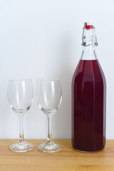 Homemade plum wine with glasses on white background