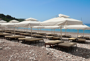 Fototapeta na wymiar Umbrellas on Sveti Stefan beach, one of the most beautiful beaches in Montenegro. Europe