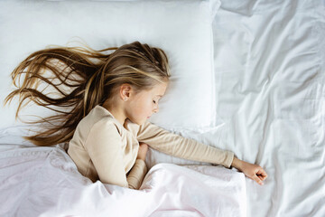 Candid lifestyle portrait of caucasian child eight years old in pajamas sleeping in bed at cozy...