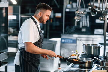 Flames on the frying pan. Chef is on the kitchen preparing food
