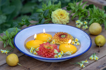Schwimmkerzen und Dahlienblüten im vintage Emaille-Teller im Garten