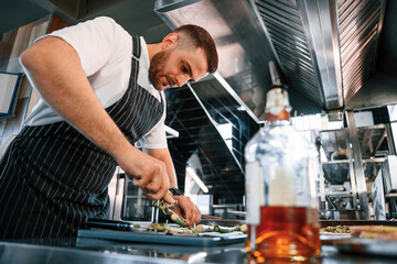 Slicing and cutting asparagus. Chef is on the kitchen preparing food