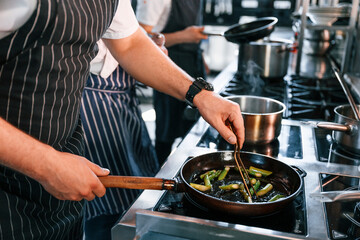 Side view. Kitchen workers is together preparing the food