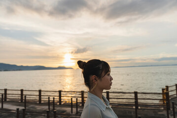 夕暮れの海を散策する女性