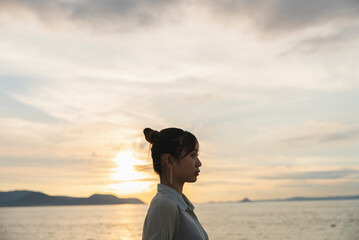 夕暮れの海を散策する女性