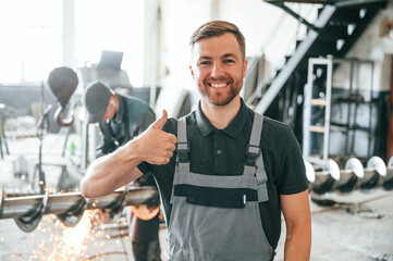 Standing and smiling. Man in uniform is in workstation developing details of agriculture technique